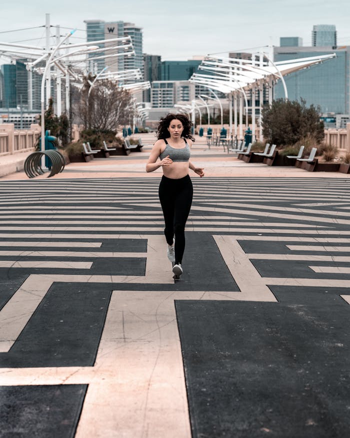 Woman in activewear jogging on a city path, showcasing urban fitness lifestyle.